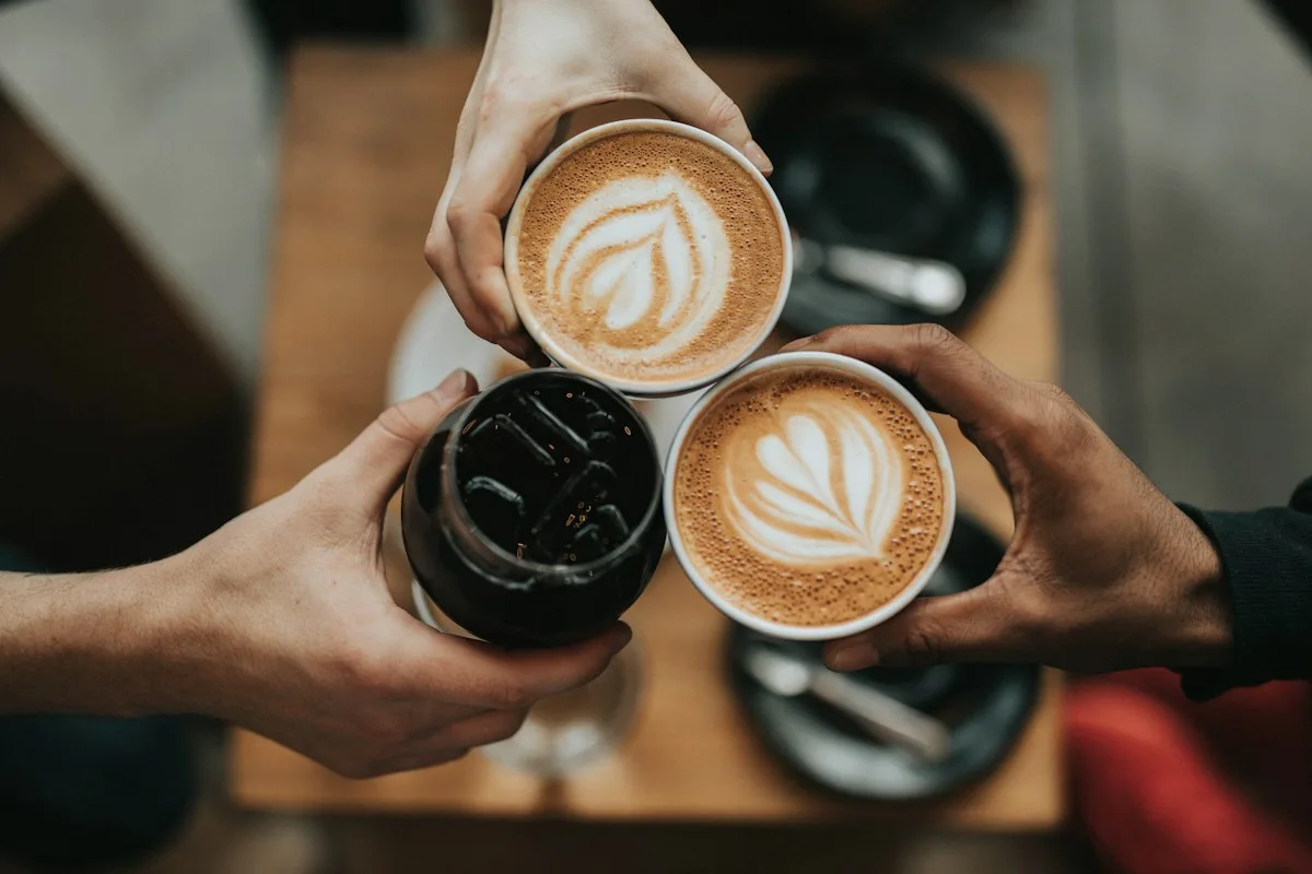 Hands coming together over three freshly made coffees